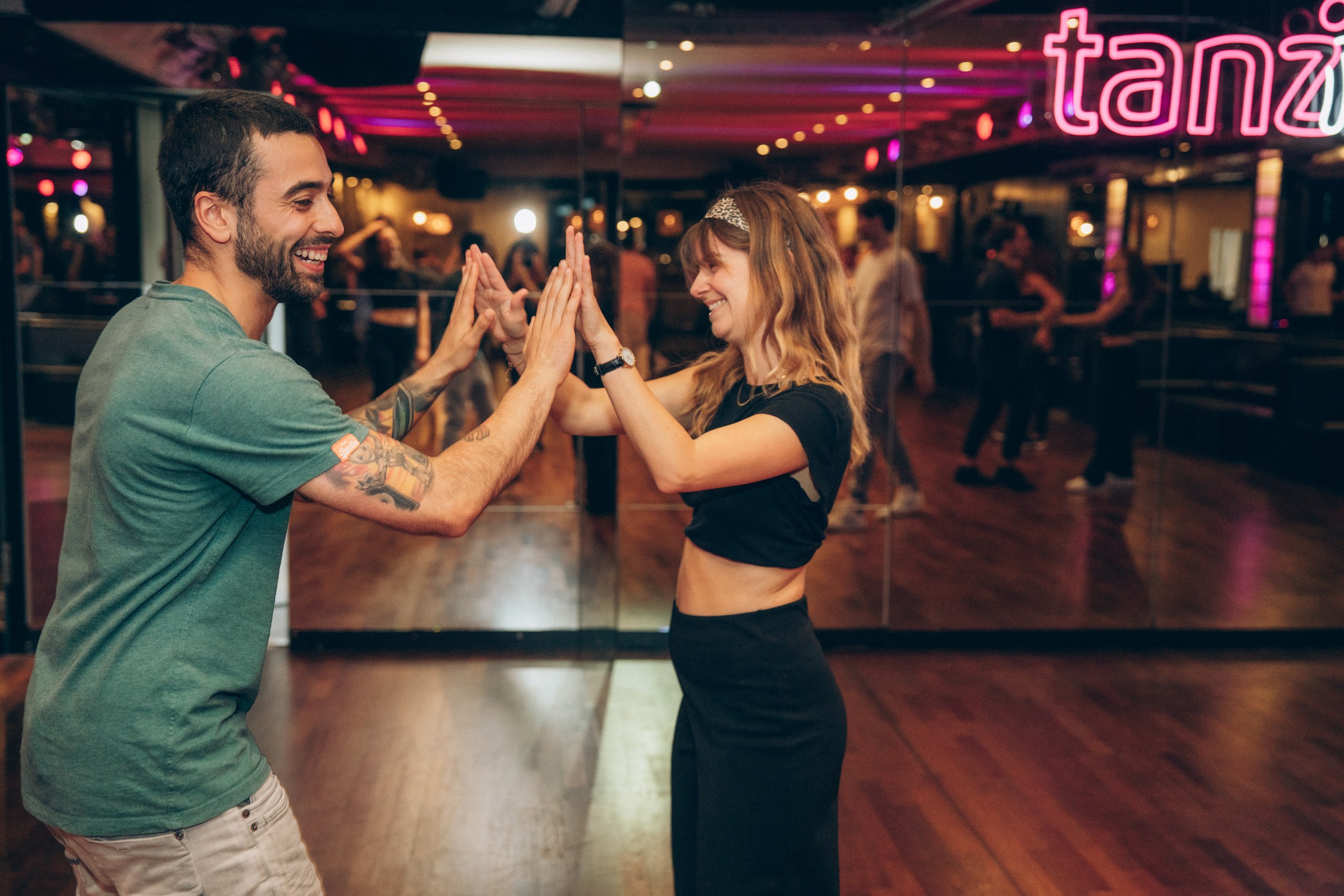 Zwei Menschen klatschen ab während eines Bachata-Sensual-Unterrichts in einer Tanzschule in Köln.