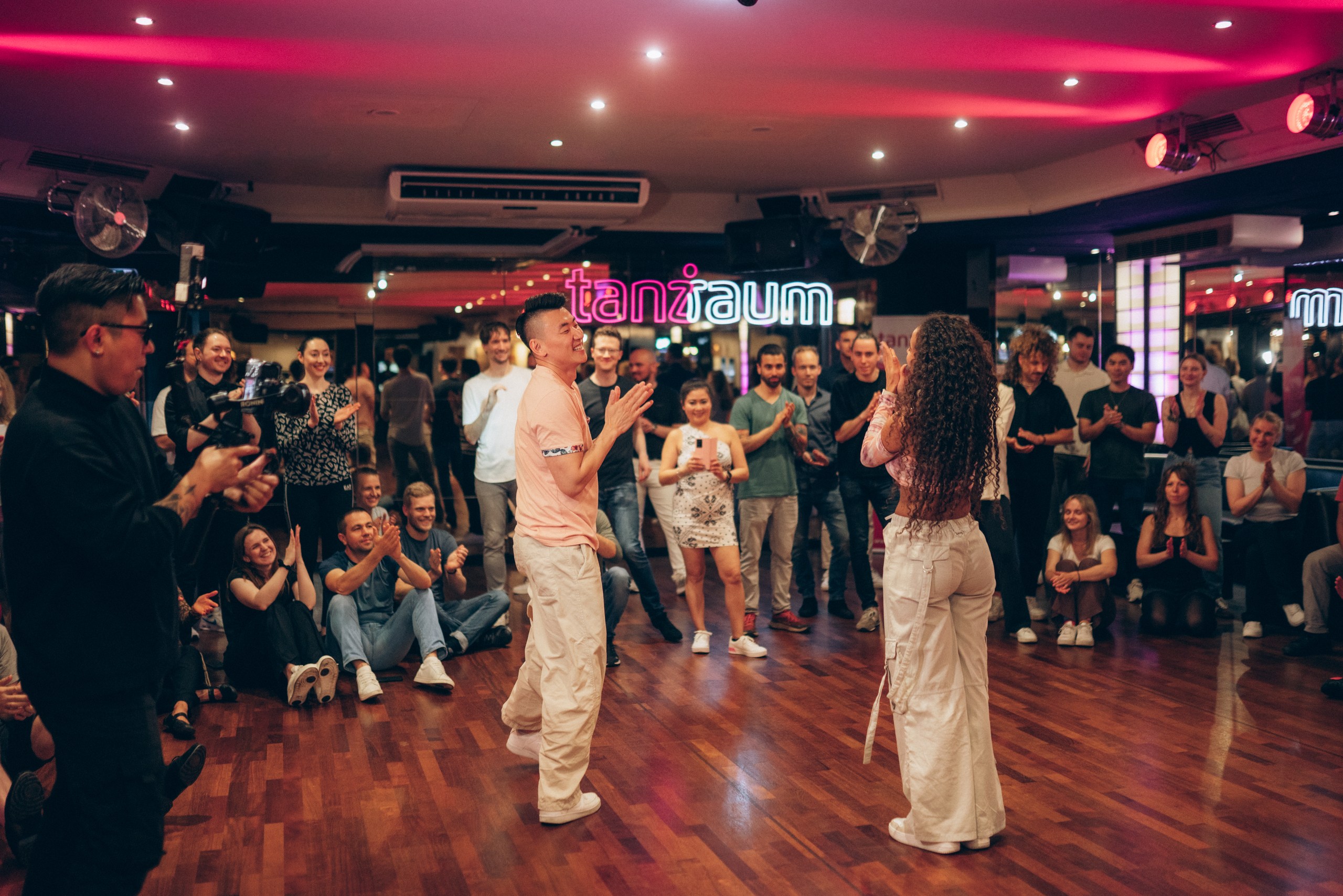 Zwei Bachata-Lehrer lächeln nach dem Bachata-Unterricht in Köln, während die Schüler zuschauen